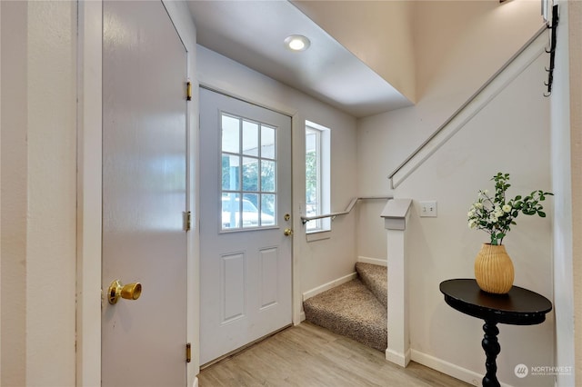 doorway to outside featuring light wood-style flooring, baseboards, and stairs