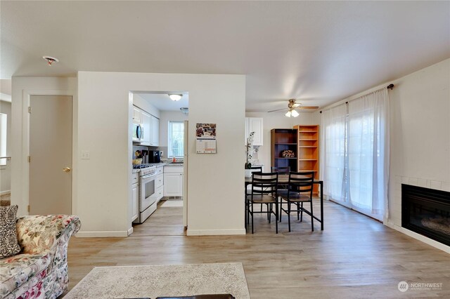 interior space with light wood-type flooring, ceiling fan, and a tile fireplace