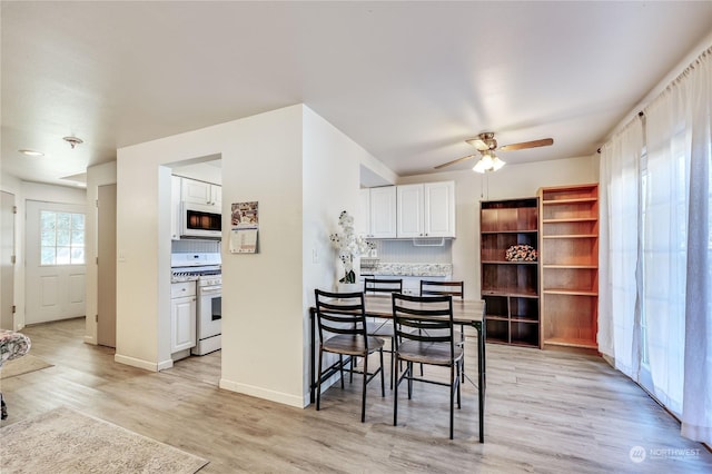 dining area with light wood-style floors, ceiling fan, and baseboards