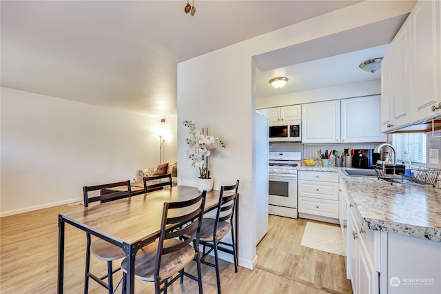 kitchen featuring white gas stove, a sink, and white cabinets