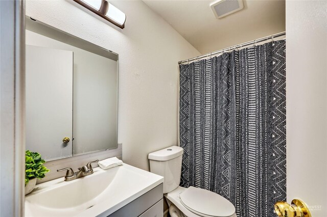 bathroom featuring walk in shower, toilet, and vanity