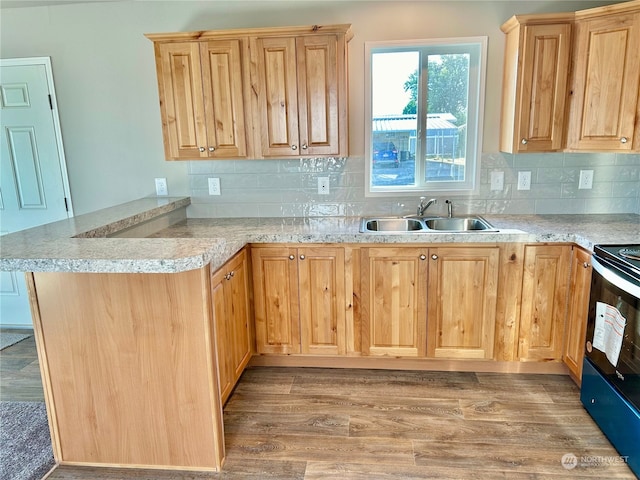 kitchen featuring kitchen peninsula, hardwood / wood-style flooring, tasteful backsplash, and sink