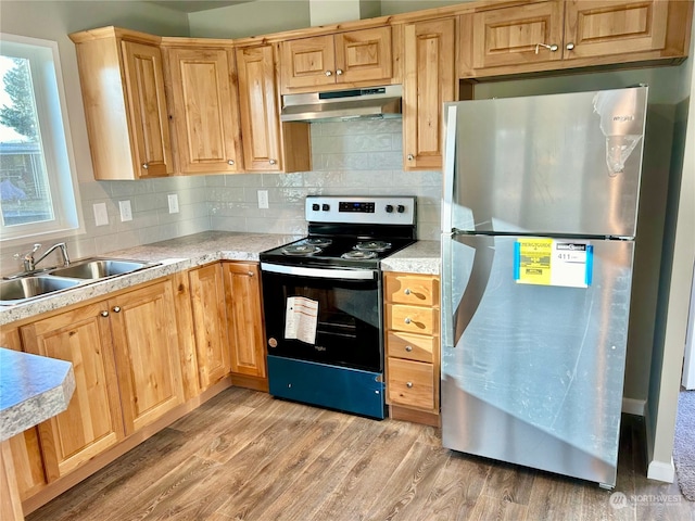 kitchen featuring stainless steel fridge, light hardwood / wood-style floors, backsplash, black electric range, and sink