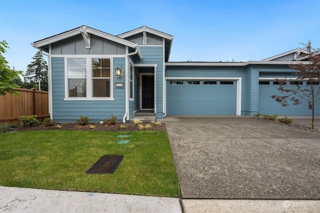 view of front of home with concrete driveway, an attached garage, fence, a front lawn, and board and batten siding