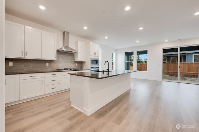 kitchen with wall chimney range hood, dark countertops, appliances with stainless steel finishes, and decorative backsplash