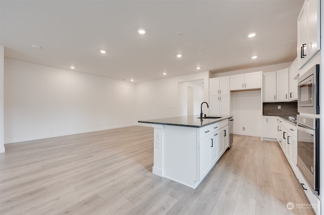 kitchen with stainless steel appliances, dark countertops, light wood-style floors, and a sink