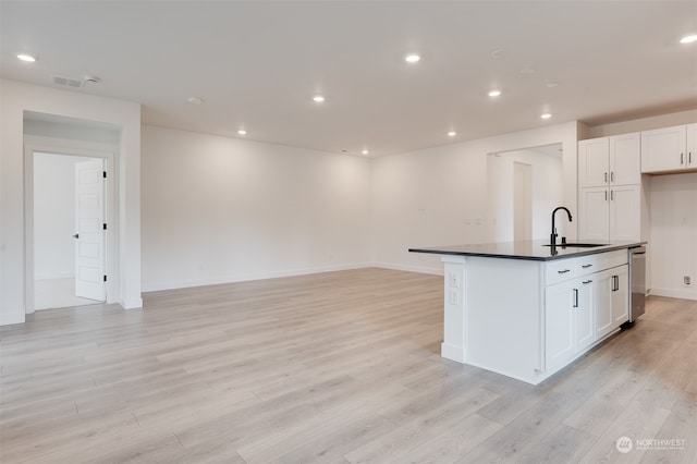 kitchen with white cabinets, light wood-type flooring, sink, and an island with sink