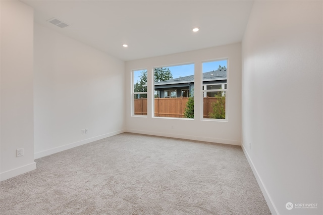 empty room featuring recessed lighting, baseboards, and light colored carpet