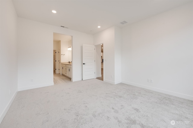 unfurnished bedroom with recessed lighting, visible vents, light carpet, ensuite bath, and baseboards