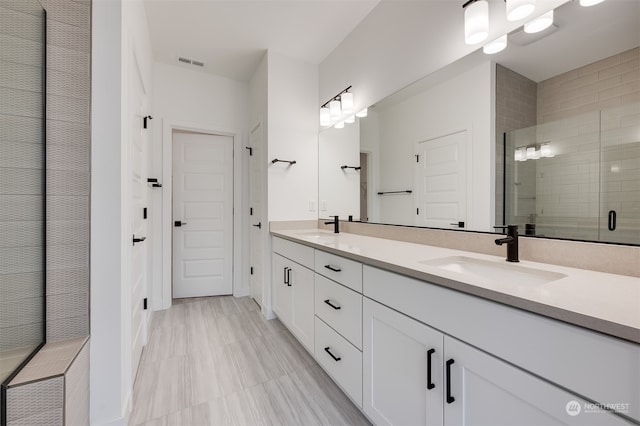 full bath featuring visible vents, a sink, a shower stall, and double vanity