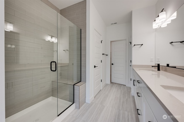 bathroom featuring a stall shower, visible vents, a sink, and double vanity