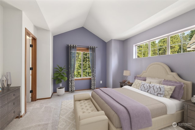 bedroom featuring multiple windows, lofted ceiling, and light colored carpet