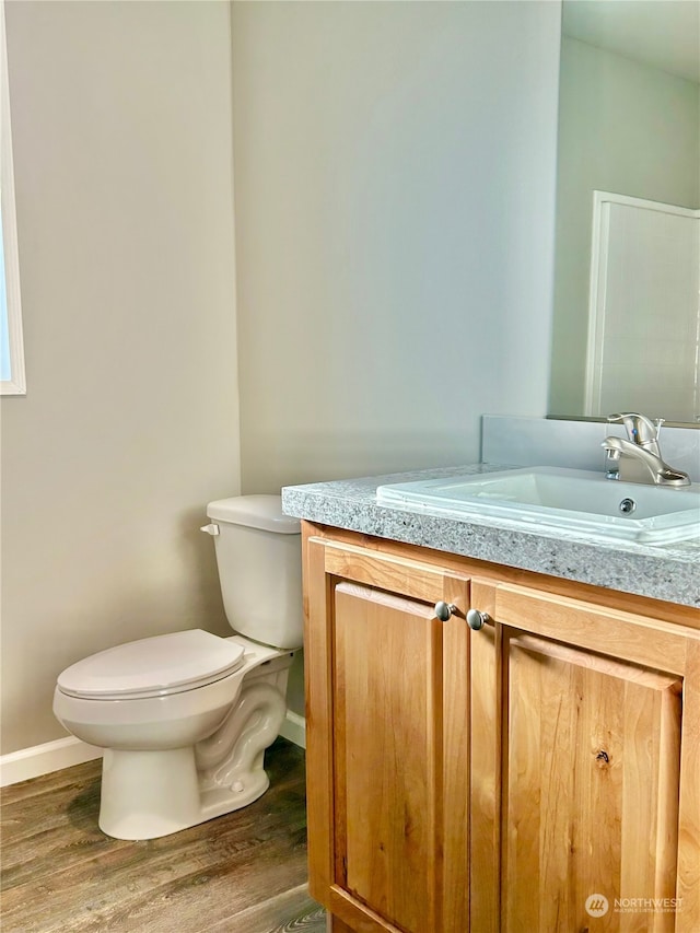 bathroom with wood-type flooring, vanity, and toilet