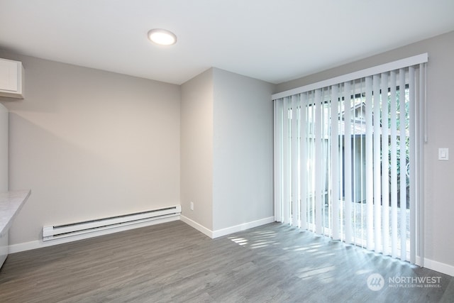 unfurnished room featuring a baseboard heating unit, a healthy amount of sunlight, and hardwood / wood-style floors