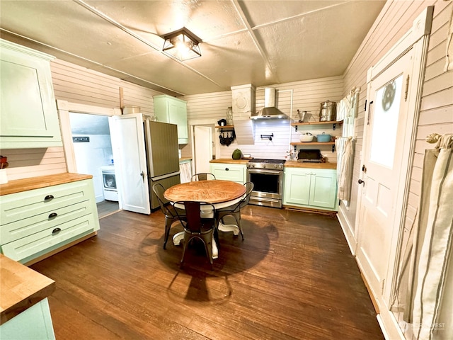 kitchen with stainless steel appliances, wood walls, butcher block countertops, and wall chimney exhaust hood