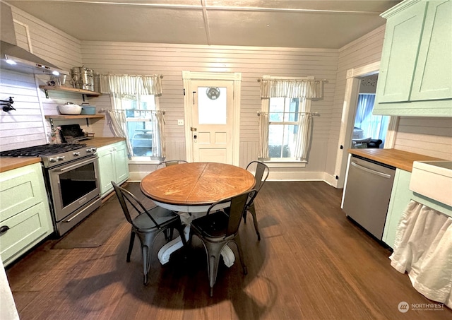 kitchen with appliances with stainless steel finishes, wood counters, and wood walls