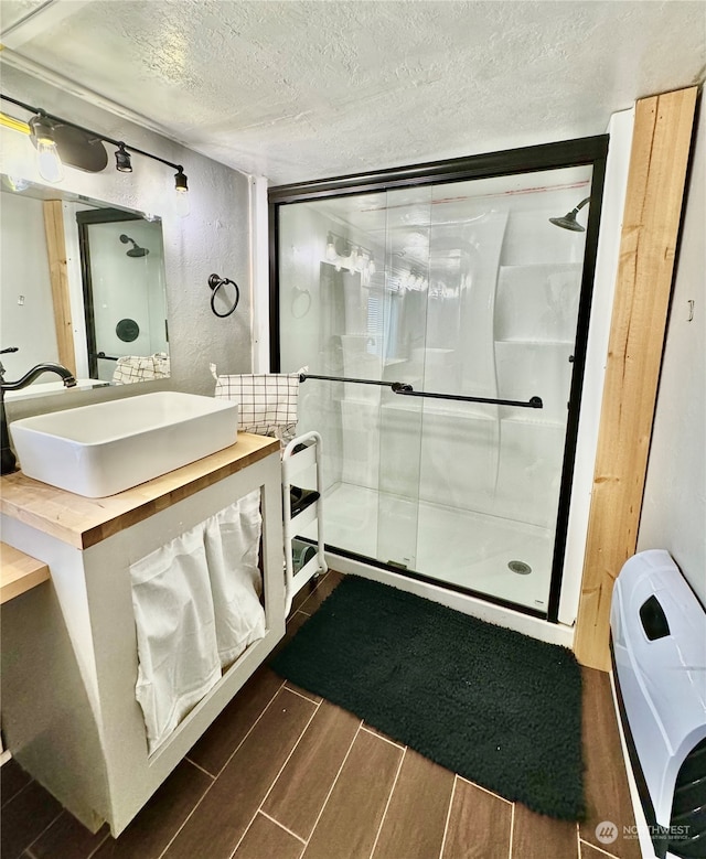 bathroom featuring an enclosed shower, hardwood / wood-style flooring, a textured ceiling, and vanity