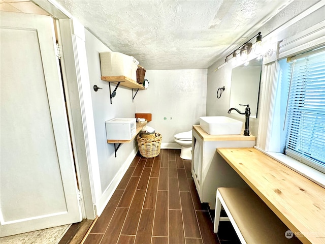 bathroom featuring vanity, toilet, wood-type flooring, and a textured ceiling