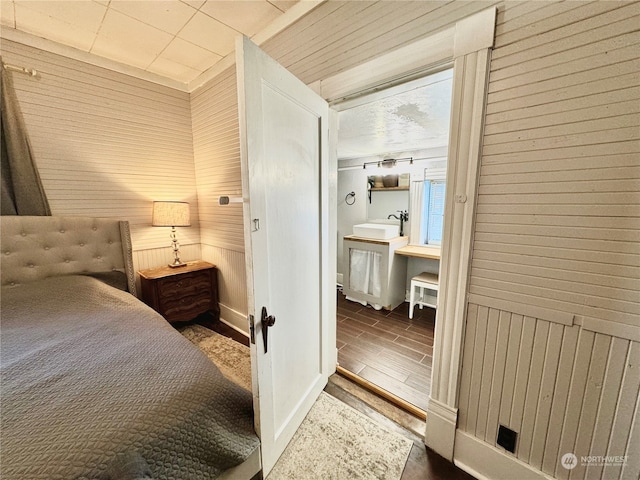 bedroom featuring dark hardwood / wood-style flooring, wood walls, and sink