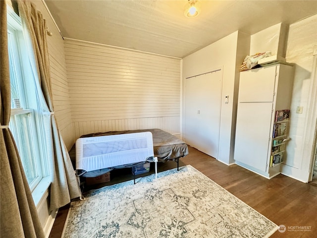 bedroom featuring wood walls, dark hardwood / wood-style floors, and heating unit