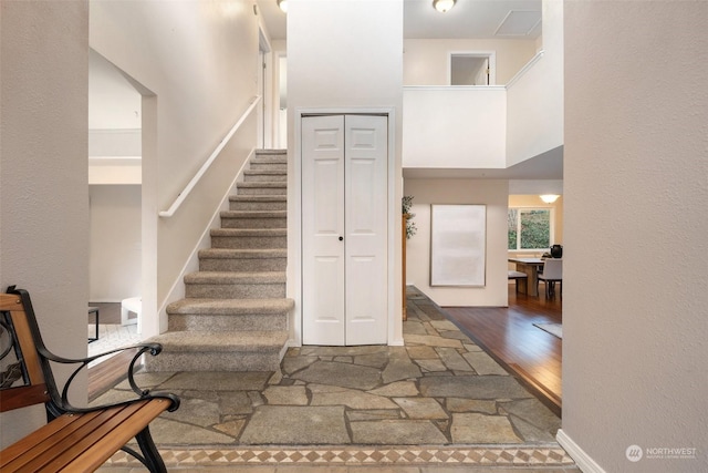 stairs featuring wood-type flooring and a high ceiling