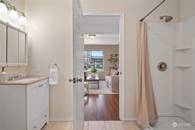 bathroom with walk in shower, vanity, and tile patterned flooring