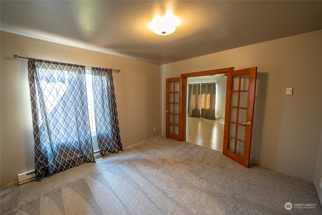 empty room featuring baseboard heating, carpet, and french doors