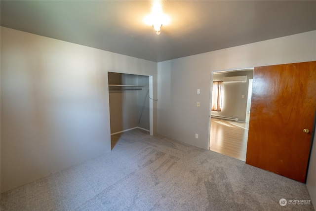 unfurnished bedroom featuring carpet flooring, a wall unit AC, a baseboard radiator, and a closet