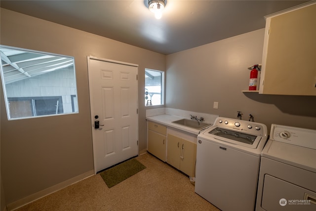 clothes washing area with light carpet, washing machine and clothes dryer, cabinets, and sink