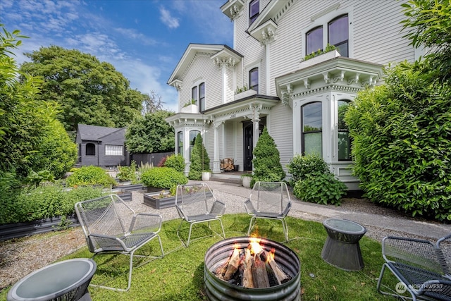 rear view of house featuring a lawn and a fire pit