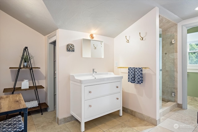 bathroom with a textured ceiling, vanity, tile patterned flooring, and walk in shower