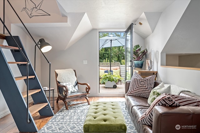 living area with lofted ceiling, light wood-type flooring, and a textured ceiling