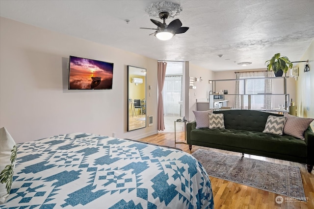 bedroom featuring a textured ceiling, ceiling fan, and light hardwood / wood-style floors