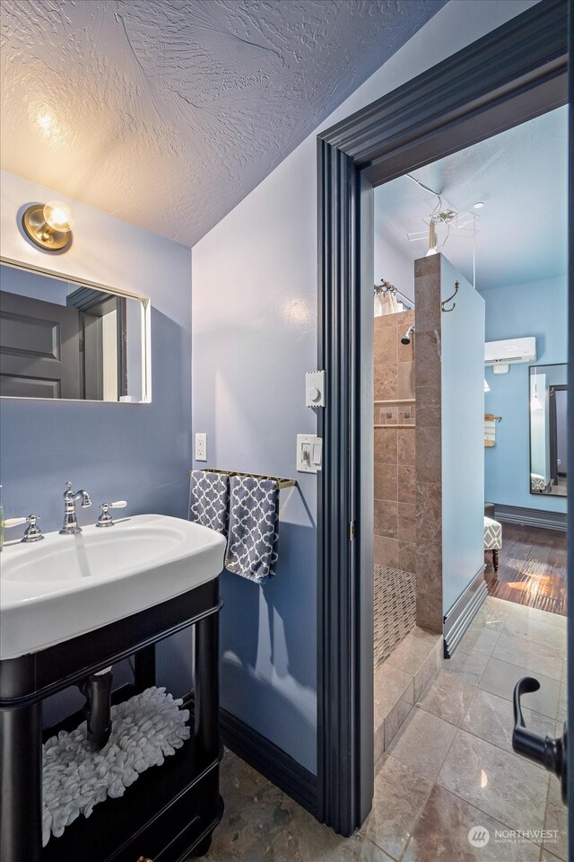 bathroom with tiled shower, vanity, hardwood / wood-style floors, and a textured ceiling