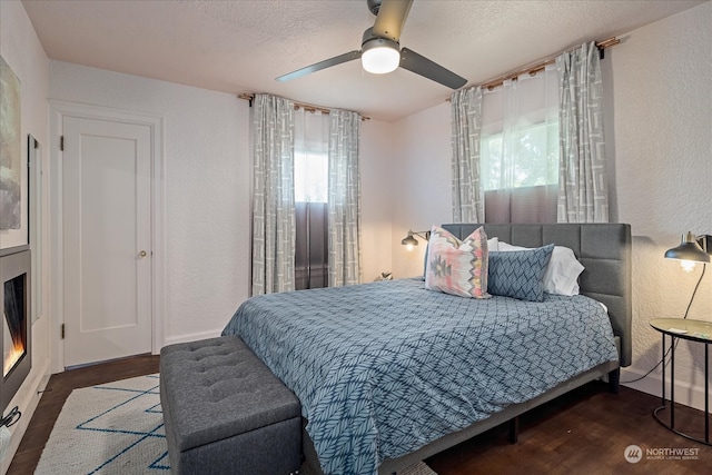 bedroom with ceiling fan, dark hardwood / wood-style floors, and a textured ceiling