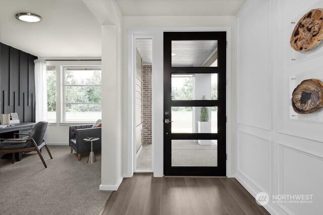 foyer with dark wood-type flooring, baseboards, and dark colored carpet