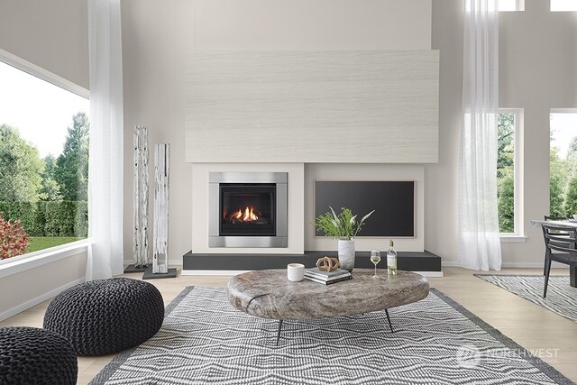 interior space with a glass covered fireplace, baseboards, and light wood-type flooring