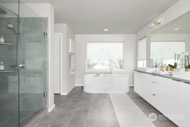 bathroom featuring a shower stall, tile patterned flooring, baseboards, a soaking tub, and vanity