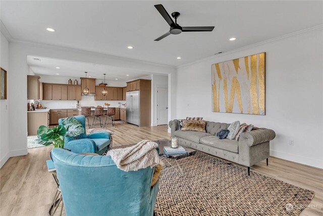 living room featuring ceiling fan, ornamental molding, and light hardwood / wood-style floors