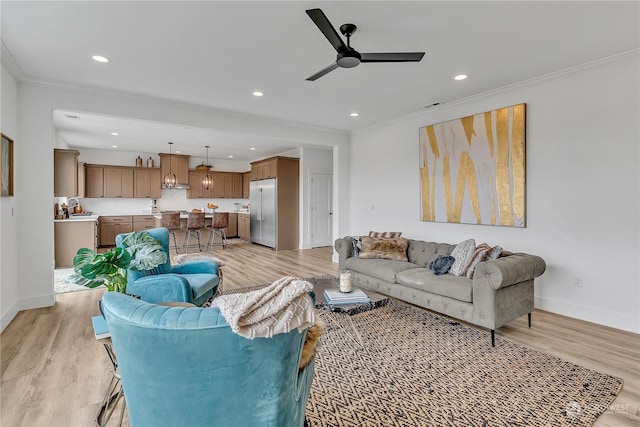 living room featuring ceiling fan, baseboards, light wood-style floors, and ornamental molding