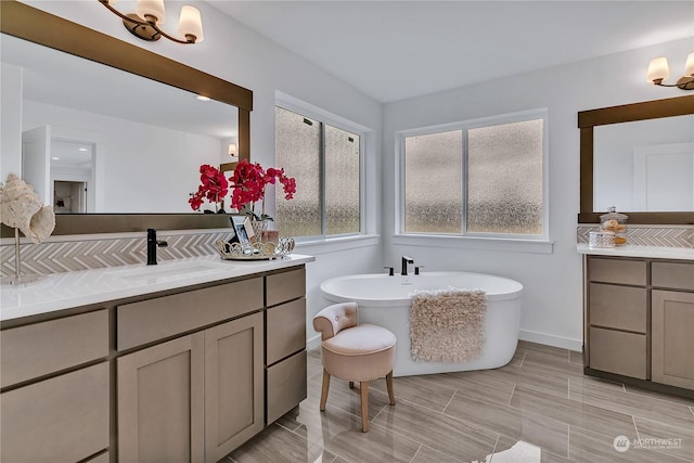 bathroom featuring a sink, a freestanding tub, baseboards, and two vanities