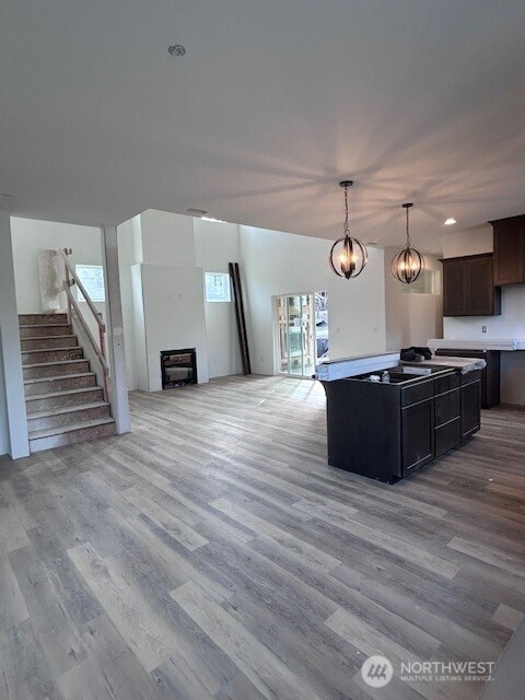 kitchen with a glass covered fireplace, light wood-style flooring, hanging light fixtures, and open floor plan