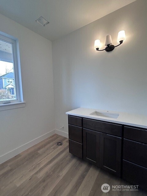 bathroom with an inviting chandelier, vanity, baseboards, and wood finished floors