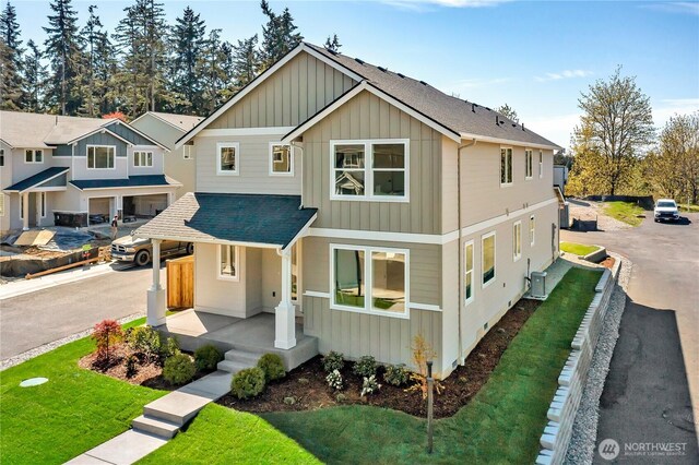 16212 76th Avenue Ct E, Puyallup, WA 98375 - view of front facade with roof with shingles, a front lawn, cooling unit, covered porch, and board and batten siding
