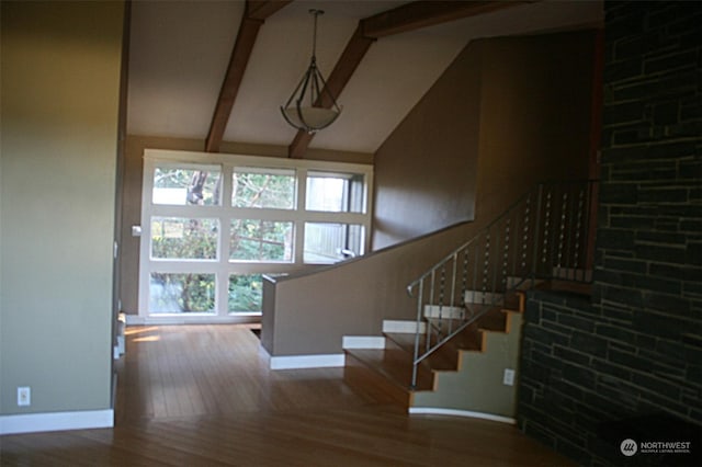 stairs featuring beamed ceiling, hardwood / wood-style flooring, and high vaulted ceiling