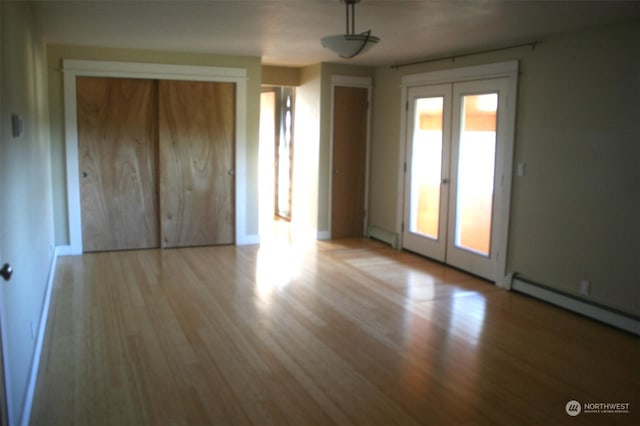 interior space featuring french doors, light wood-type flooring, and baseboard heating