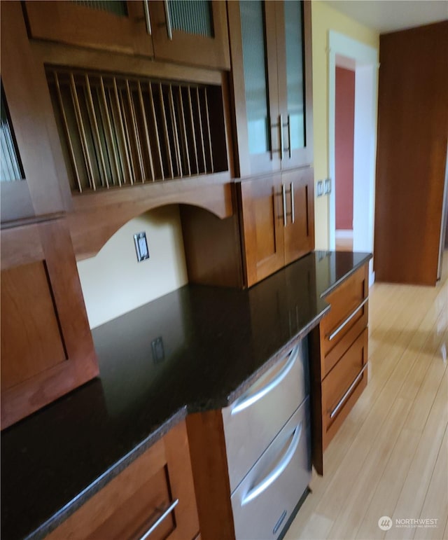 kitchen with light hardwood / wood-style floors and dark stone countertops