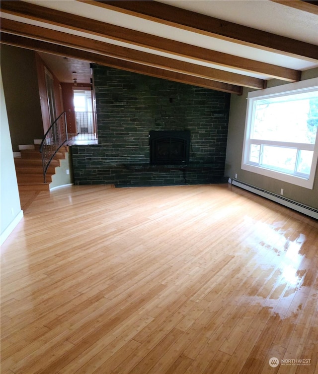 unfurnished living room with a fireplace, a healthy amount of sunlight, light hardwood / wood-style floors, and baseboard heating