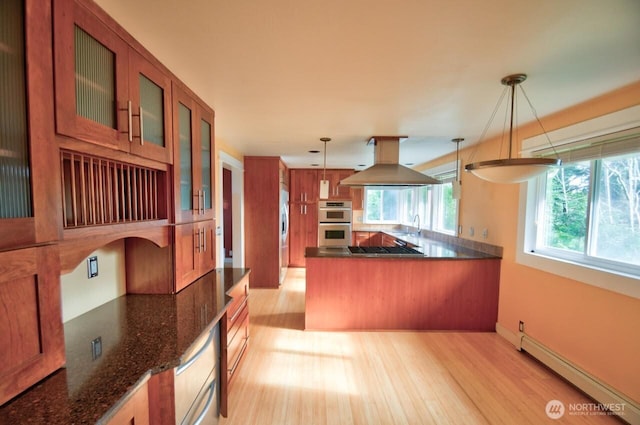 kitchen featuring appliances with stainless steel finishes, a baseboard radiator, brown cabinets, and island range hood