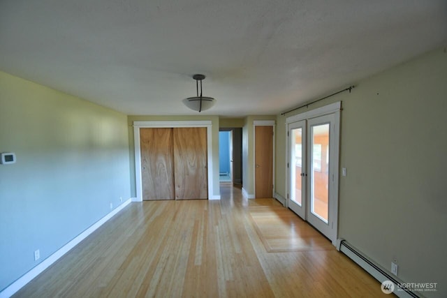 unfurnished bedroom with a baseboard radiator, access to exterior, baseboards, light wood-style floors, and french doors